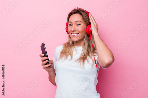 Young australian woman listening to music isolated on pink background