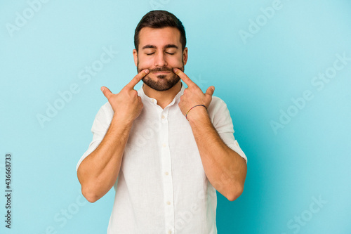 Young caucasian man isolated on blue background doubting between two options.