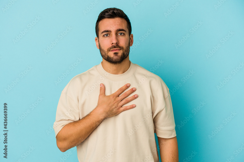 Young caucasian man isolated on blue background taking an oath, putting hand on chest. Young caucasian man isolated on blue background taking an oath, putting hand on chest.
