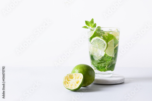 Classic mojito cocktail with lime isolated on white light background. Summer freshness beverage for festive party. Holiday mocktail with copy space.