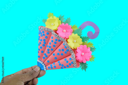 Blue and pink colored handmade crafted umbrella placed on a blue paper