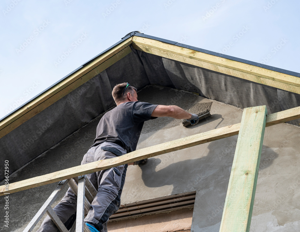 Construction worker plastering the facade of the house
