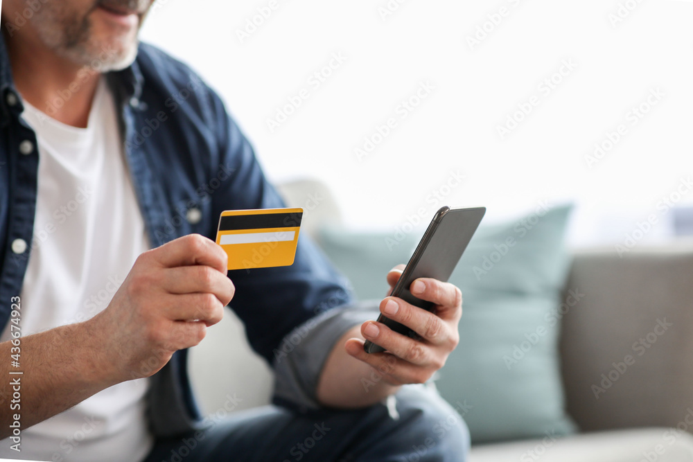 Unrecognizable man using smartphone and holding credit card Unrecognizable man using smartphone and holding credit card