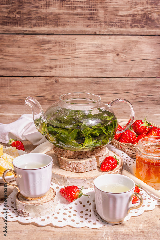 Teatime concept with aromatic mint tea, ripe strawberries, sweet honey Teatime concept with aromatic mint tea, ripe strawberries, sweet honey