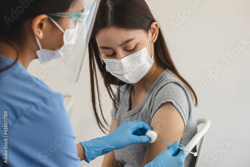 People getting a vaccination to prevent pandemic concept. Woman in medical face mask  receiving a dose of immunization coronavirus vaccine from a nurse at the medical center hospital photo