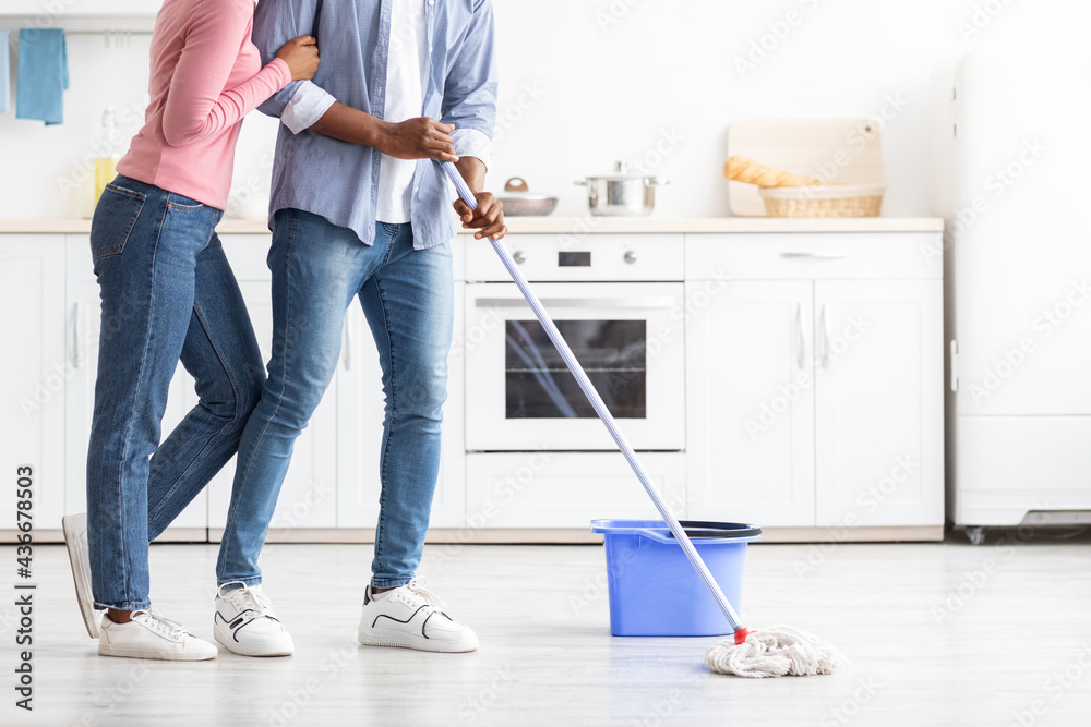 Cropped of black couple mopping floor in kitchen Cropped of black couple mopping floor in kitchen