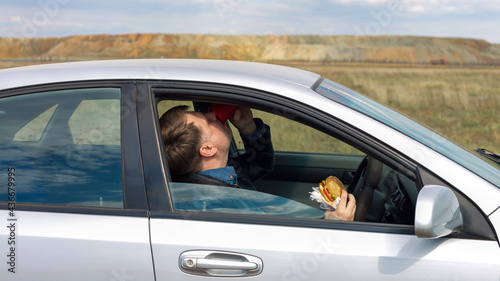 The manager eats lunch at wheel in the car.
