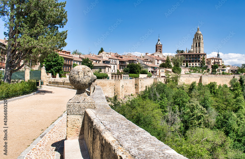 Fototapeta premium Paseo peatonal bordeando las murallas medievales de Segovia con vista de la torre campanario de la catedral, España