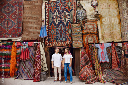 Couple in love buys a carpet and handmade textiles at an oriental market in Turkey. Hugs and cheerful happy faces of men and women