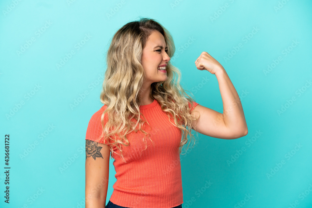 Young Brazilian woman isolated on blue background doing strong gesture