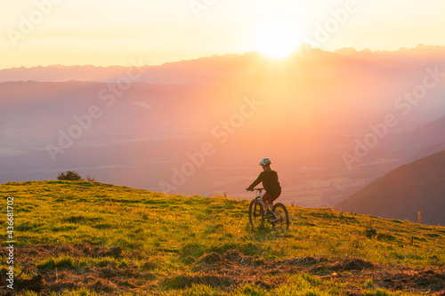 Girl child riding mountain bike into the sunset. Beautiful golden summer light. © 24K-Production