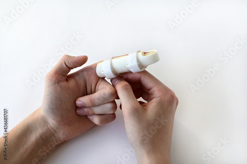 hands of a teenager with a medical splint on a broken finger, on a white background. Medical assistance in case of injury.