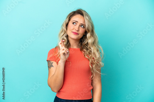 Young Brazilian woman isolated on blue background with fingers crossing and wishing the best © luismolinero