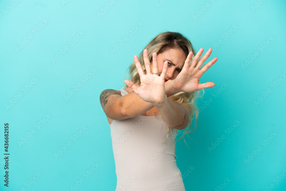 Young Brazilian woman isolated on blue background nervous stretching hands to the front