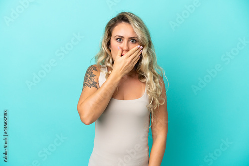 Young Brazilian woman isolated on blue background covering mouth with hand