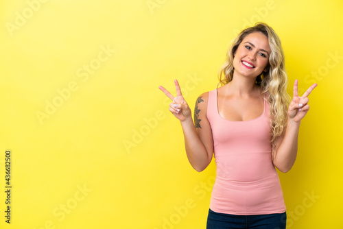 Young Brazilian woman isolated on yellow background showing victory sign with both hands