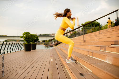 Young woman jumping on the stairs at the riverside © BGStock72