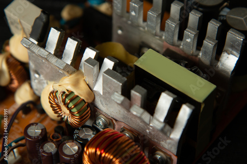 Part of pc power supply with radiator and electronic board with integrated stabilizers and filter capacitor with coils.