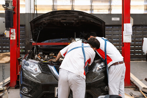 mechanic is checking the car in automobile repair service center with soft-focus and over light in the background