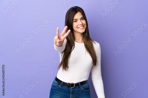 Teenager Brazilian girl over isolated purple background happy and counting three with fingers