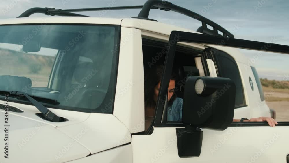 A confident woman is getting out from the jeep after arriving to the lake