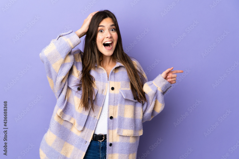 Teenager Brazilian girl over isolated purple background surprised and pointing finger to the side Teenager Brazilian girl over isolated purple background surprised and pointing finger to the side
