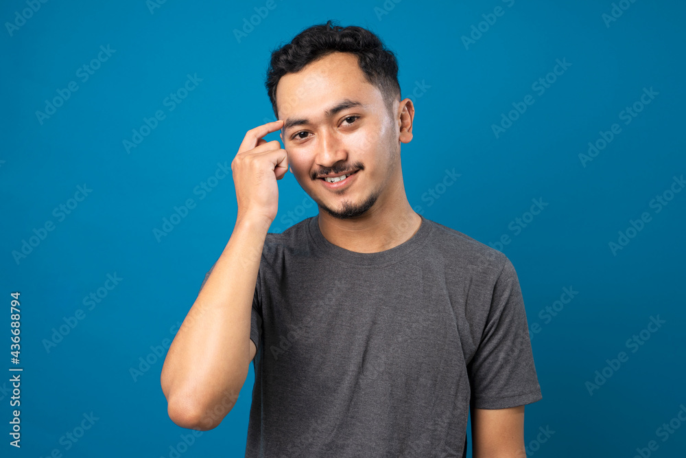 Young handsome man with beard wearing casual t-shirt over blue background Smiling pointing to head with one finger, great idea or thought, good memory Young handsome man with beard wearing casual t-shirt over blue background Smiling pointing to head with one finger, great idea or thought, good memory