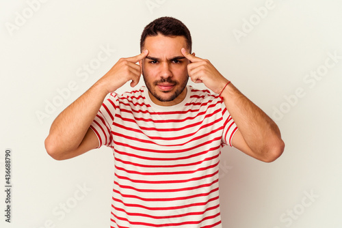 Young caucasian man isolated on white background focused on a task, keeping forefingers pointing head.