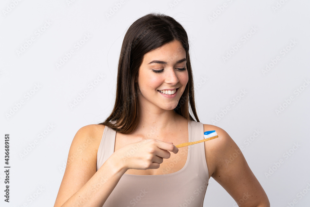 Teenager Brazilian girl brushing her teeth over isolated white background Teenager Brazilian girl brushing her teeth over isolated white background