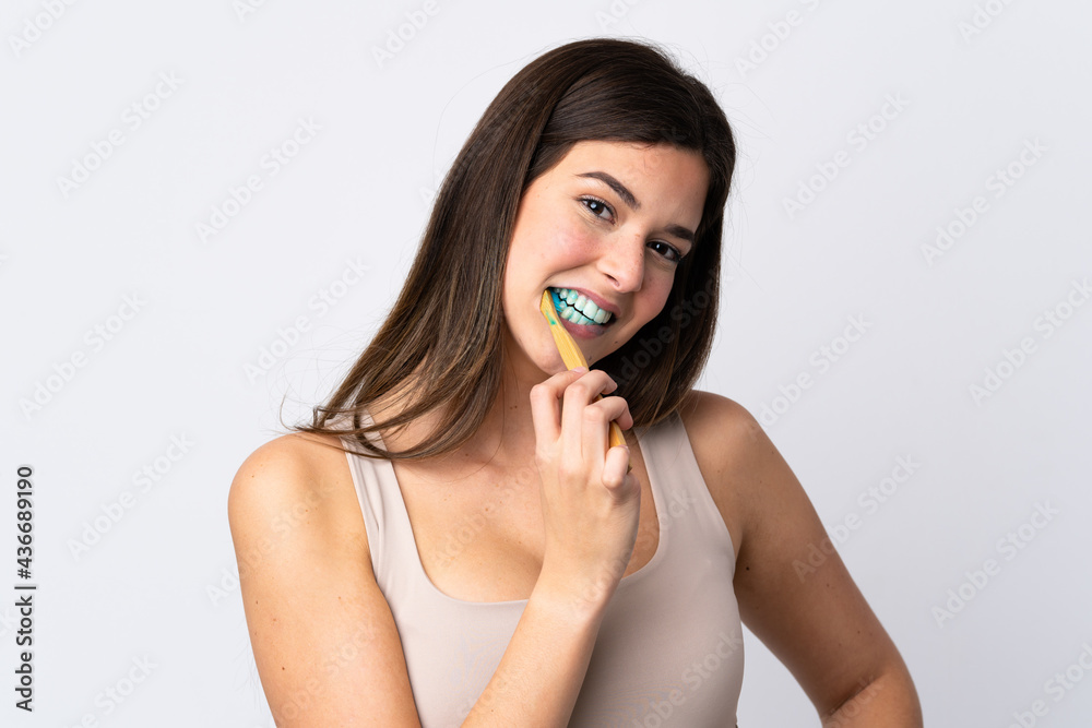 Teenager Brazilian girl brushing her teeth over isolated white background