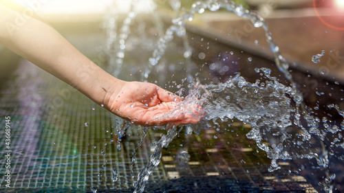Kids hand and stream, splash of clean pure water. World environment day or World oceans day concept. Refreshing ecologically water in summer heat sunny day. © Elena
