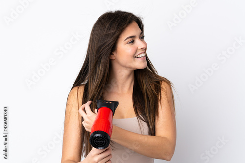 Teenager Brazilian girl with hairdryer over isolated white background