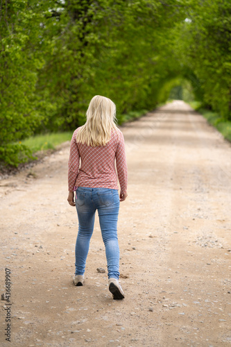 Girl blonde on the road somewhere going, tree arch
