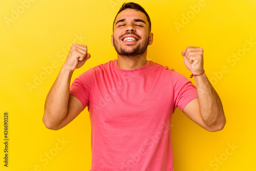 Young caucasian man isolated on yellow background celebrating a victory, passion and enthusiasm, happy expression.