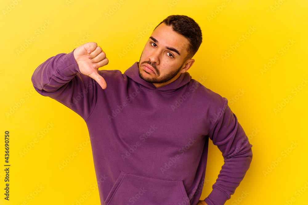Young caucasian man isolated on yellow background showing thumb down, disappointment concept. Young caucasian man isolated on yellow background showing thumb down, disappointment concept.