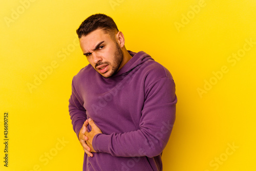 Young caucasian man isolated on yellow background having a liver pain, stomach ache.