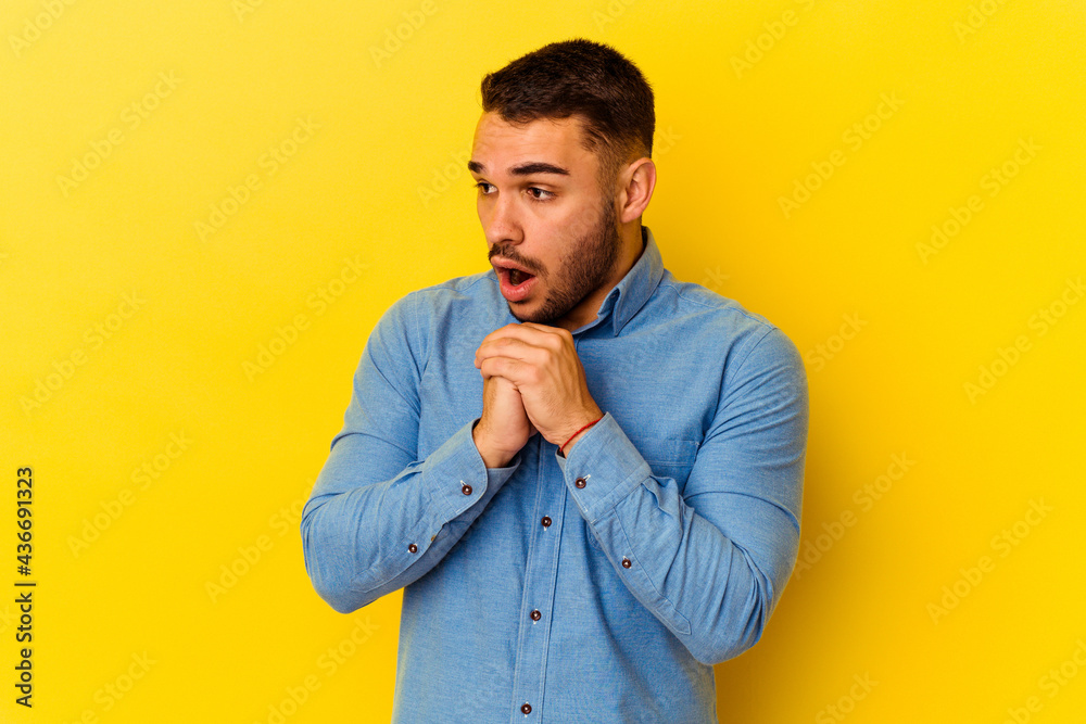 Young caucasian man isolated on yellow background praying for luck, amazed and opening mouth looking to front. Young caucasian man isolated on yellow background praying for luck, amazed and opening mouth looking to front.