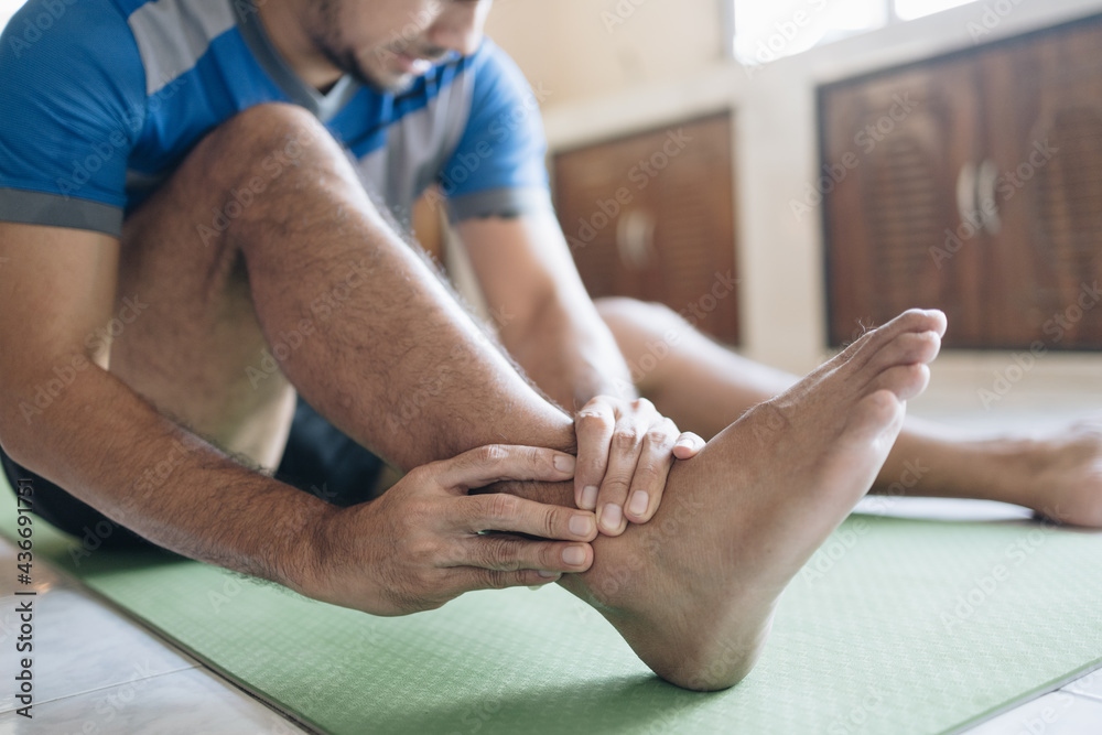 man feeling pain in the ankle from exercising at home man feeling pain in the ankle from exercising at home