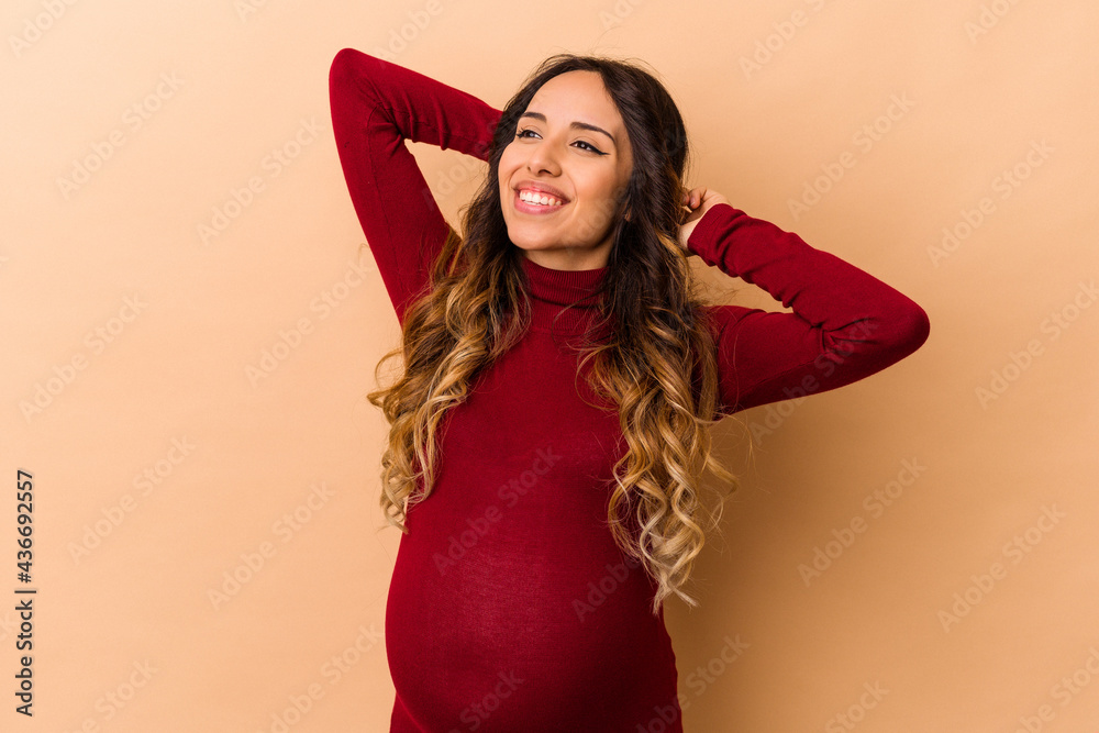 Young mexican pregnant woman isolated on beige background stretching arms, relaxed position. Young mexican pregnant woman isolated on beige background stretching arms, relaxed position.