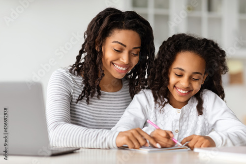 Happy black mother helping daughter with homework