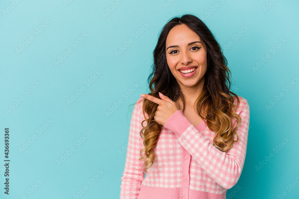 Young mexican woman isolated on blue background smiling and pointing aside, showing something at blank space. Young mexican woman isolated on blue background smiling and pointing aside, showing something at blank space.