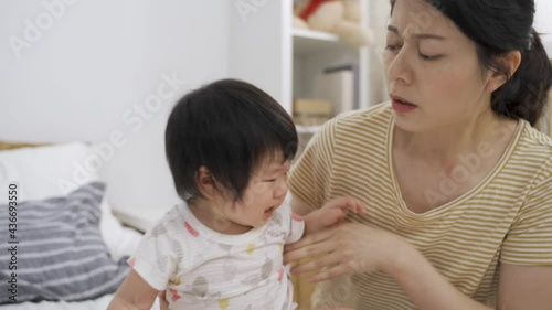 closeup asian mom waving hand with a gross look at the smelly bottom is picking up her fussy toddler child to leave and change nappy in the bedroom.