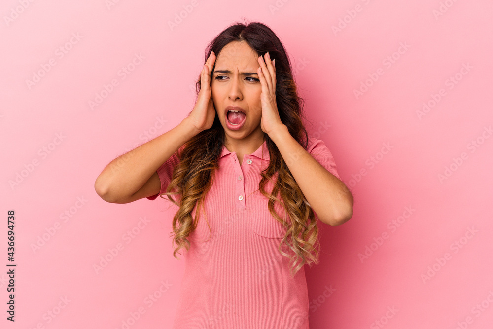 Young mexican woman isolated on pink background covering ears with hands trying not to hear too loud sound. Young mexican woman isolated on pink background covering ears with hands trying not to hear too loud sound.