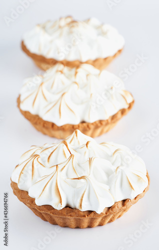 Lemon Curd and Meringue Mini Tarts Pies on white background, selective focus, copy space. Bakery pastry dessert concept.