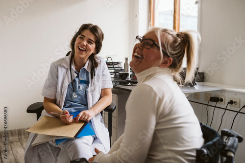 Cheerful female healthcare worker and disabled patient looking away photo
