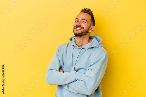 Young tattooed caucasian man isolated on yellow background laughing and having fun.