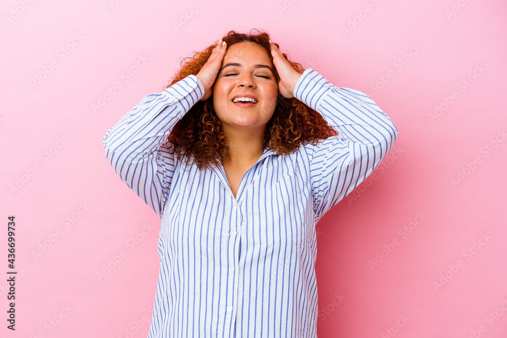 Young latin curvy woman isolated on pink background laughs joyfully keeping hands on head. Happiness concept.