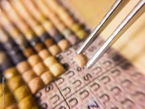 metal tweezers hold a piece of diamond mosaic