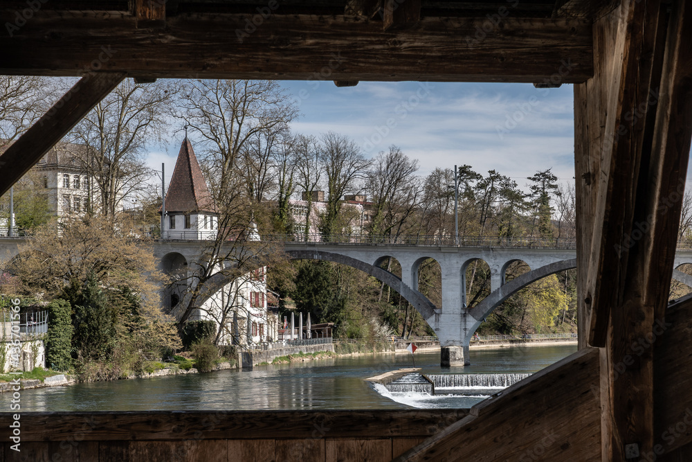 View over Reuss river to white tower called Katzenturm and rail viaduct in Bremgarten at springtime.