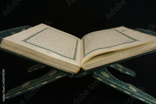 Photo of an open Islamic holy book against a black background and incoming light. suitable as a photo with the theme of religion and events of Islam or Ramadan
